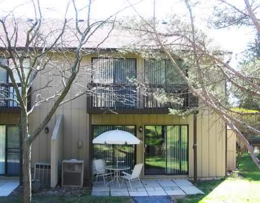Front view of a two-story house with large sliding glass doors and a small patio area.