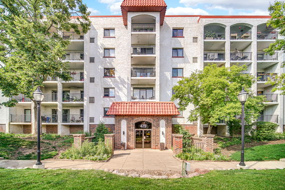 Front view of a multi-story building with balconies and a tiled roof entrance.