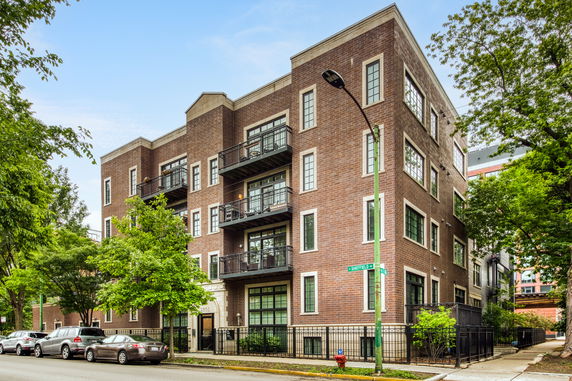 Front view of a multi-story brick apartment building with balconies.