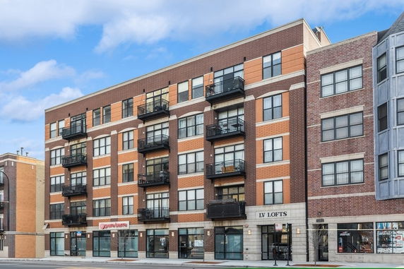 Front view of a multi-story brick building with balconies and storefronts.