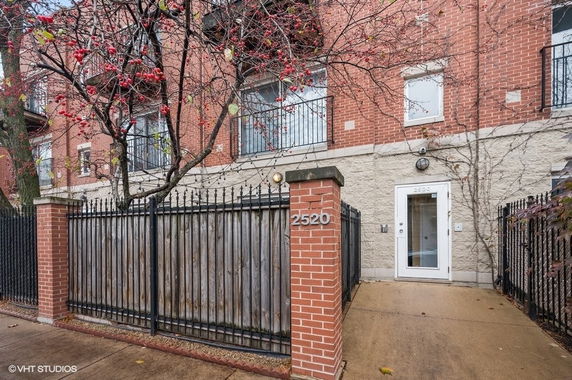 Front view of a multi-story brick building with a gated entrance.