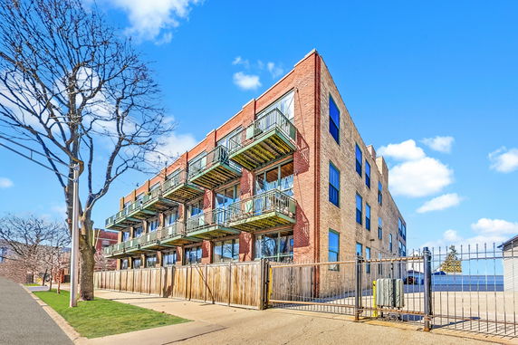 Front view of a multi-story brick building with balconies and large windows