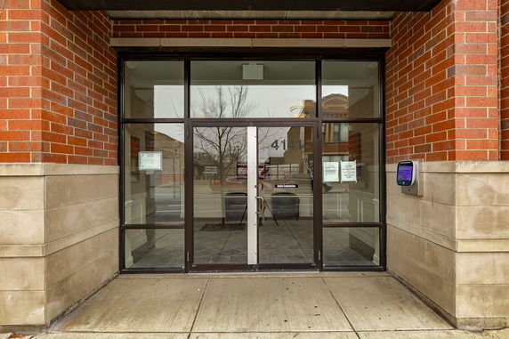 Front view of a building entrance with glass doors and brick exterior.