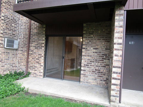 View of a brick building with a sliding glass door and an air conditioning unit.