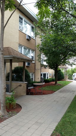 Front view of a multi-story brick building with several windows and air conditioning units.