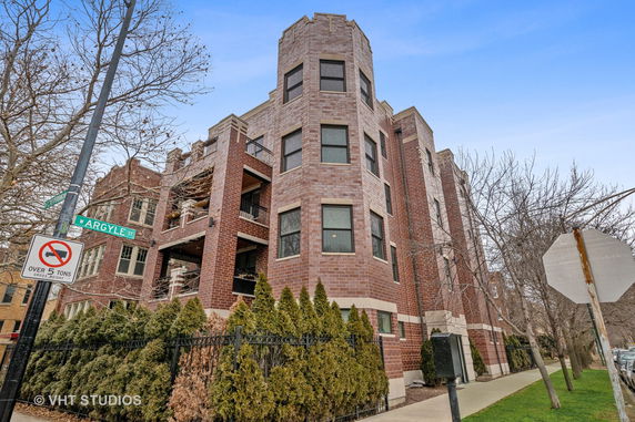Front view of a multi-story brick residential building with multiple balconies.