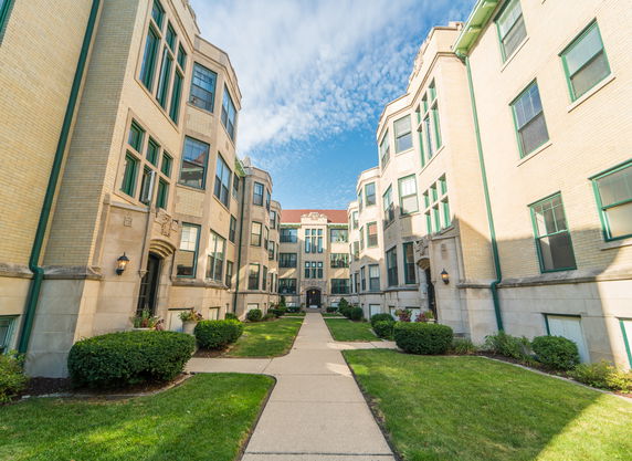 Front view of two adjacent multi-story buildings with a walkway in between.