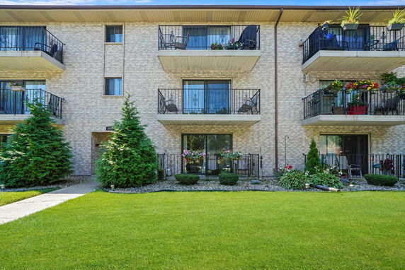 Front view of a multi-story building with balconies and green landscaping.