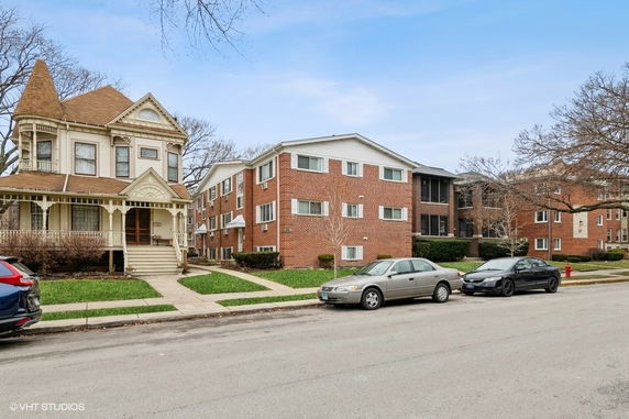 Front view of a two-story Victorian-style house next to a three-story brick apartment building.