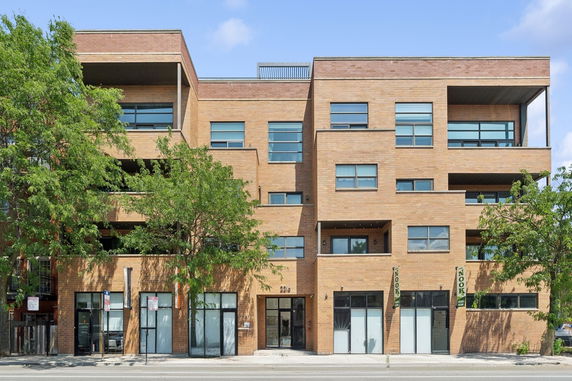 Front view of a multi-story brick building with large windows.