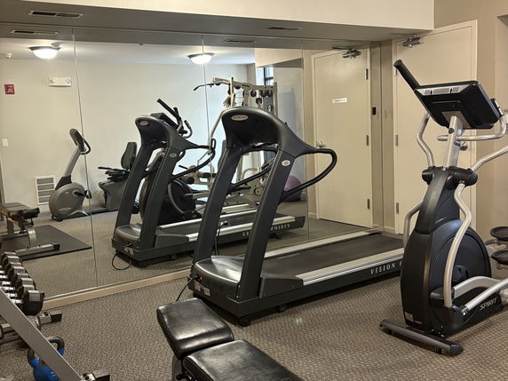 Indoor gym area with exercise equipment including treadmills and weights.