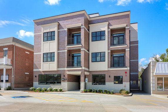 Front view of a three-story brick building with large windows.