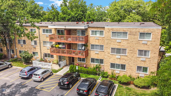 Front view of a three-story apartment building with balconies and parking area.