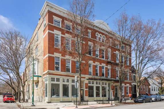 Front view of a multi-story brick building with large windows.