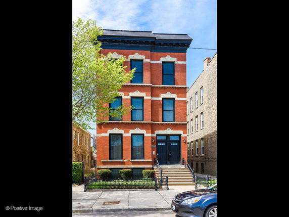 Front view of a multi-story brick building with decorative moldings and large windows.