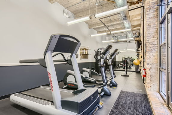 Indoor gym area with exercise machines and equipment.