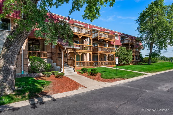 Front view of a multi-story building with wooden balconies and red roofing.