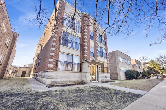 Front view of a multi-story brick apartment building with balconies.