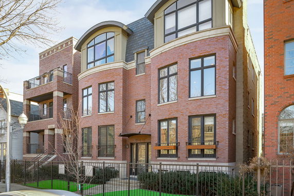 Front view of a multi-story brick building with large windows and a curved roof section.
