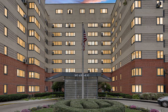 Front view of a multi-story building with a flagpole in front.