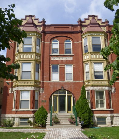 Front view of a three-story brick building with bay windows and ornate design.