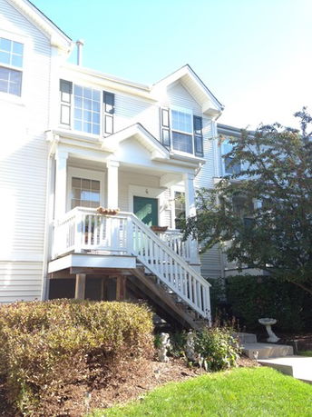 Front view of a two-story house with a small porch and staircase.