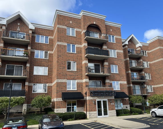 Front view of a multi-story apartment building with brick exterior and balconies.