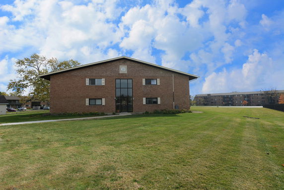 Front view of a two-story brick building with large central window and gable roof.