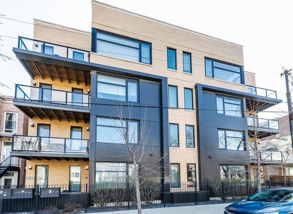 Front view of a modern multi-story building with large windows and balconies.