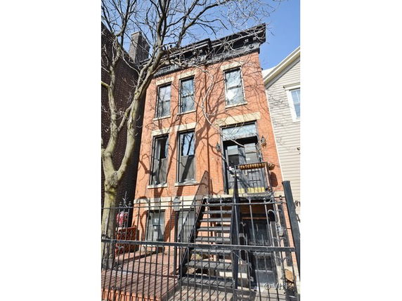 Front view of a three-story brick building with external staircase.