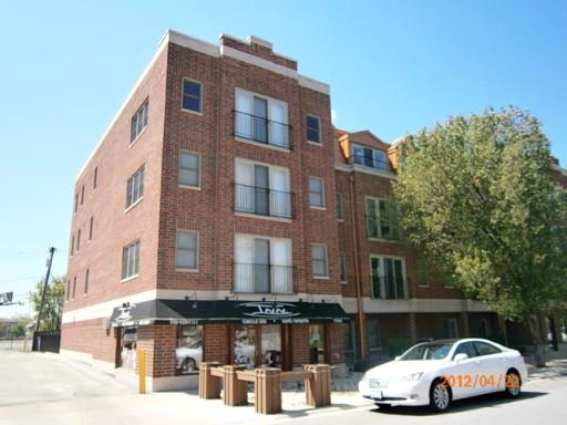 Front view of a four-story brick building with a commercial space on the ground floor and balconies on the upper floors.
