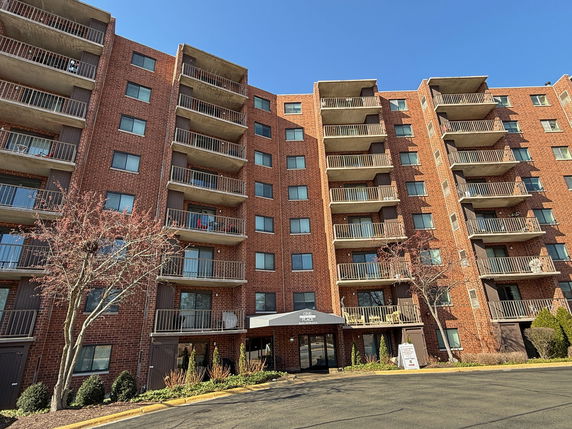Front view of a multi-story brick apartment building with balconies.