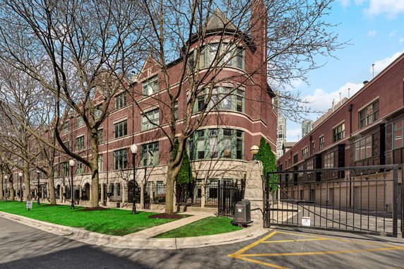 Front view of a multi-story brick residential building with large windows and an iron fence.