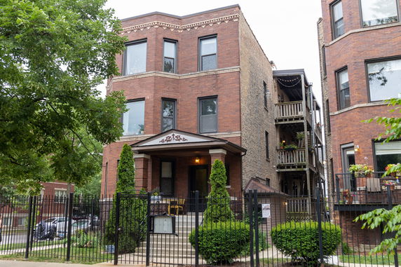 Front view of a three-story brick building with decorative trim and a front porch.