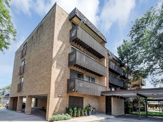 Front view of a multi-story brick apartment building with balconies.