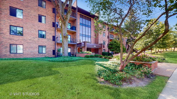 Front view of a multi-story brick building with balconies and large windows.