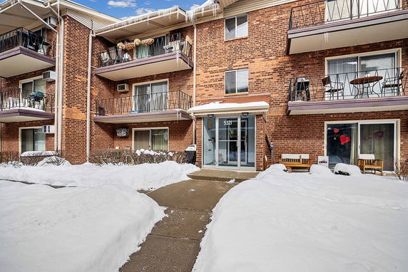 Front view of a brick multi-story apartment building with balconies.