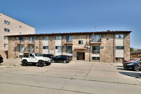 Front view of a two-story brick apartment building with multiple balconies.