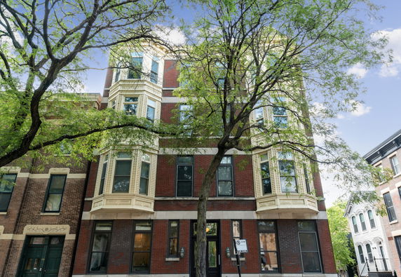 Front view of a multi-story brick building with bay windows.
