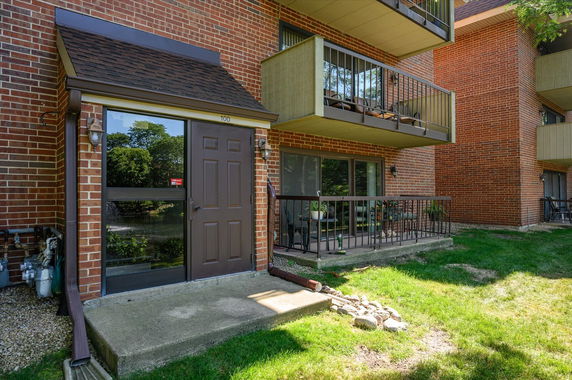 Front view of a brick building with balconies and a brown entrance door.