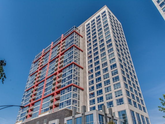 Front view of a modern high-rise building with large windows and red accents.