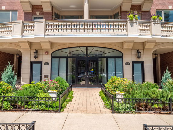 Front view of a building entrance with glass doors and decorative balconies.