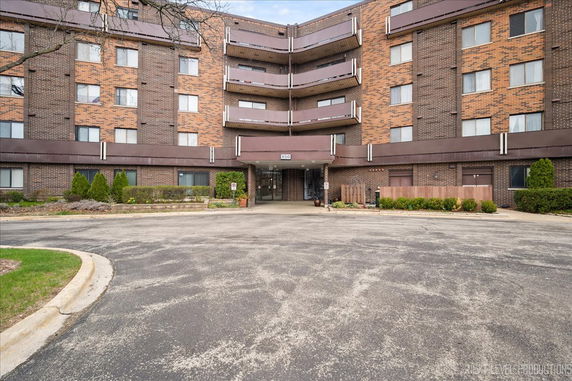 Front view of a multi-story brick apartment building with balconies.