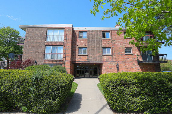 Front view of a three-story brick apartment building with balconies.