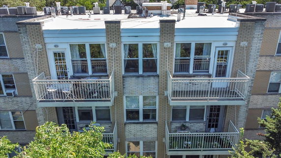 Front view of a multi-story building with balconies and rooftop features.