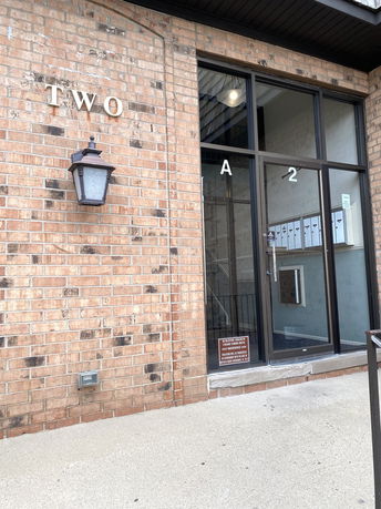 Front view of a building entrance with brick exterior and glass door.