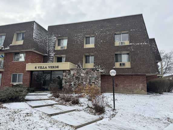 Front view of a brick apartment building with multiple floors and a sign labeled '6 Villa Verde'.