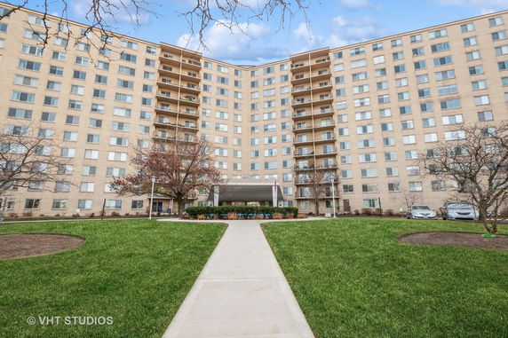Front view of a multi-story apartment building with balconies and a central entrance.