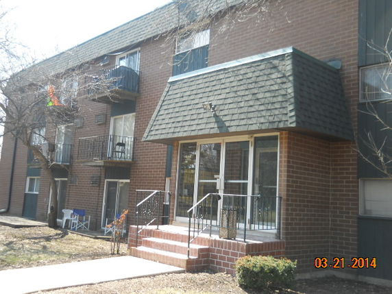 Front view of a multi-story brick apartment building with balconies and a central entrance.