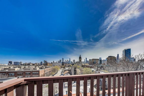 Panoramic view of a city skyline from a rooftop with a wooden railing.